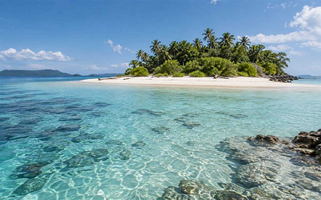 A quiet tropical island with white sand and clear turquoise shallows