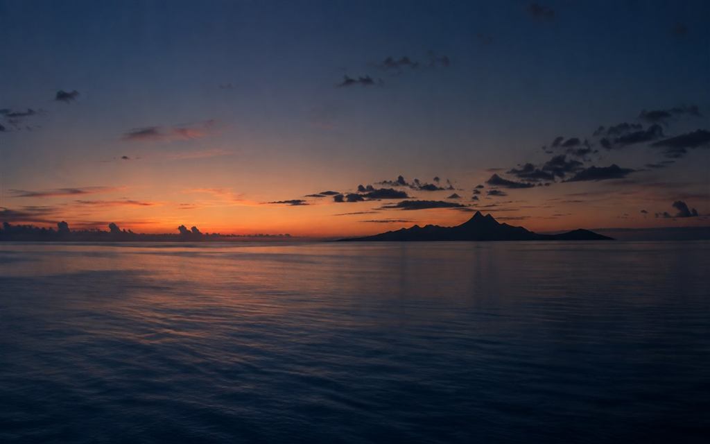 Quiet dusk light over calm water and a tropical island silhouette